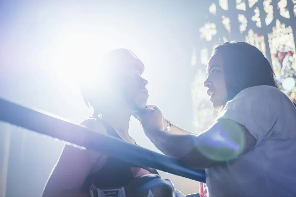 person fixing person's boxing headgear in the ring